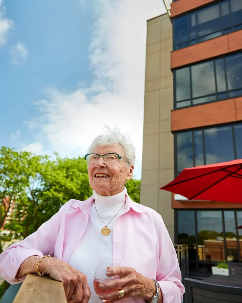 A senior outside smiling with a drink